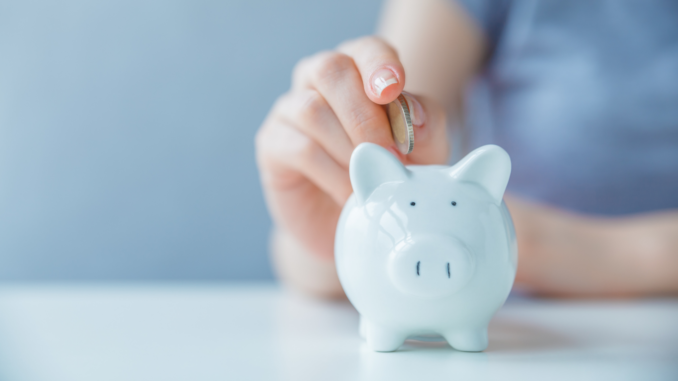 Frau wirft eine Münze in ein Sparschwein (über cozmo news)