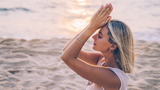 Frau meditiert am Strand (über Anna Tarazevich)